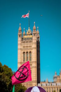 Extinction rebellion flag in front of Westminster and English flag, during a global strike for climate change.
